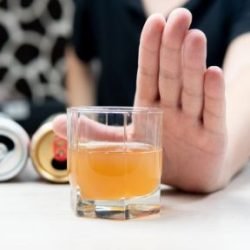 Hand raised to refuse an alcoholic drink — choosing abstinence